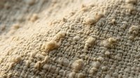 Close-up macro shot of textured beige carpet fibers showing detailed weave pattern and natural fabric construction for interior design concepts.