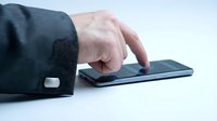 Caucasian male hand in dark business suit sleeve touching smartphone screen on white background for technology and communication concepts.