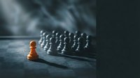 Golden pawn standing alone facing silver chess pieces on board, representing leadership, strategy, competition, and business success in corporate environments.