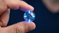 Hand holding glowing blue globe sphere with illuminated continents and digital network connections representing global technology and worldwide communication.
