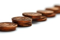 Stacked copper pennies in diagonal line formation against white background create depth perspective, selective focus on front coins for financial concept.
