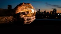 Hands holding glowing crystal ball at dusk with city skyline, symbolizing future vision, fortune telling, and business strategy concepts for design projects.
