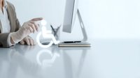 Professional businesswoman using smartphone at modern office desk with laptop computer for corporate communication and digital workflow management.
