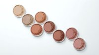 Makeup powder compacts in warm nude and brown tones arranged on white background for beauty and cosmetics branding.