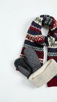 Cozy winter accessories flat lay with knitted scarf, warm mittens and wool hat on white background for seasonal fashion and cold weather styling.
