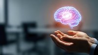 Glowing brain hologram floating above open palm in modern office setting representing artificial intelligence, innovation and mental health concepts.
