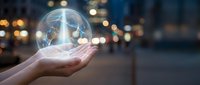 Hands holding glowing transparent sphere with world map against blurred city lights at night representing global connectivity and environmental awareness.
