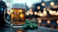 Glass mug of cold craft beer with foam head and bubbles against blurred bokeh lights background, with fresh green hop cones, moody evening atmosphere.