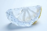 Frozen lemon slice encased in clear ice on a white background, showcasing a refreshing citrus concept for food and beverage design.