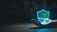 Cybersecurity shield with circuit board pattern floating above open palm on dark background for technology and data protection concepts.
