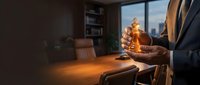 Professional businessman holding whiskey glass in modern office during golden hour with city skyline view through window for corporate lifestyle concepts.