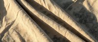 Crumpled beige linen fabric with deep shadows and natural folds, suitable for textile, fashion, and interior design backgrounds.