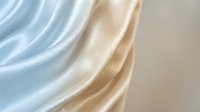 Soft flowing fabric drapes in layers of pale blue, cream, and beige tones against neutral background, suitable for textile, fashion, and design projects.