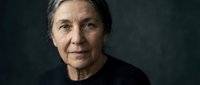 Mature woman with gray hair and fair complexion wearing black shirt against dark background, suitable for portraits, healthcare, aging, diversity, and professional headshot use.