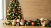 Decorated evergreen tree with gold and red ornaments beside wooden wall with festive holiday garland and baubles for seasonal celebrations and decorating projects.