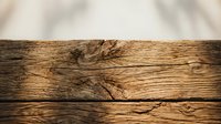 Rustic weathered wood plank with natural grain texture and cracks on neutral background for carpentry and construction projects.