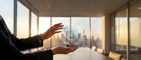 Businessman holding digital globe hologram with city skyline visible through office windows at sunset, representing global business, technology innovation, and international commerce.