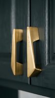 Brushed gold cabinet handles on dark navy wood doors, elegant interior hardware detail for luxury kitchen or furniture design inspiration.