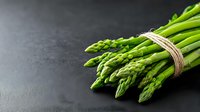 Fresh green asparagus bunch tied with twine on dark background. Raw organic vegetables with water drops for healthy cooking and menu design.