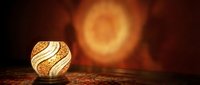 Glowing decorative orb with golden spiral pattern sits on textured surface against warm blurred light background, suitable for luxury home decor and interior design projects.