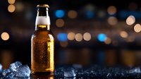 Cold beer bottle with condensation and ice cubes on dark surface against blurred bokeh lights background, refreshing alcoholic beverage photography.