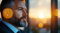Side profile of mature bearded businessman at sunset with bokeh light effects, professional corporate portrait showing confidence and leadership.