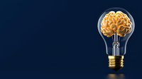 Glowing golden brain inside light bulb on dark blue background, creative intelligence and innovation concept for business solutions and ideas.