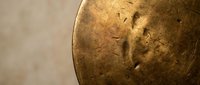 Ancient bronze coin with weathered patina showing historical engravings and oxidized surface texture on neutral background for numismatic collection displays.