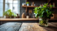 Fresh mint leaves in glass jar on rustic wooden table in cozy kitchen with natural light. Aromatic herb for cooking and beverages.