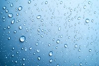 Water drops on blue gradient surface create natural pattern of scattered raindrops and condensation, showing surface tension and purity in macro view.