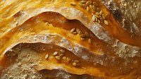 Fresh baked golden bread crust with scattered sesame seeds on top, showing detailed texture and layers of flaky pastry in macro photography.