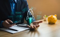 Businessman presenting holographic rocket startup concept with financial charts and piggy bank on desk representing business growth and investment planning.