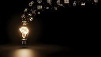 Glowing light bulb with floating business icons on dark background representing innovation, creativity and entrepreneurial ideas for marketing concepts.