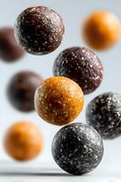 Homemade energy balls with dates nuts and seeds floating on white background. Healthy vegan protein snacks for fitness nutrition and clean eating lifestyle.