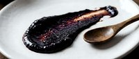 Balsamic vinegar reduction with wooden spoon on white plate for culinary, cooking, and food styling applications.