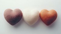 Three textured heart shapes in pink, white, and orange arranged in a row on neutral background, perfect for Valentine's Day, love themes, or romantic designs.