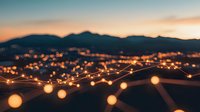Glowing string lights create magical atmosphere against mountain silhouette at dusk, with warm bokeh effects illuminating peaceful evening landscape.