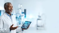 African American male doctor in white coat holding digital tablet with medical scan in modern hospital setting for healthcare technology presentations.
