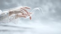 Elegant female hands with delicate lace sleeves reaching through ethereal white mist and sparkling particles creating mystical atmospheric effect for luxury branding.