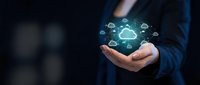 Businessman holding glowing cloud computing network with connected devices icons floating above palm in dark professional setting for technology concepts.