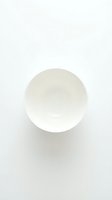 White ceramic saucer shot from above on a light background, minimalist style for food, tableware, and kitchen design projects.