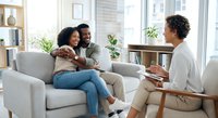 African American couple receiving counseling session from therapist in modern office setting for relationship guidance and mental health support.