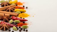 Colorful aromatic spices and herbs scattered on white background with copy space. Cinnamon sticks, star anise, cardamom pods, turmeric powder for cooking.