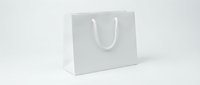 White paper shopping bag with rope handles on light background, mockup for branding, retail packaging, and gift presentation design.
