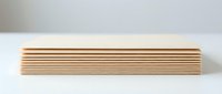 Stack of natural wooden planks or boards arranged in neat pile on white surface for construction carpentry and woodworking projects.