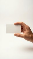 Hand holding blank white business card mockup against neutral beige background for branding and corporate identity design projects.