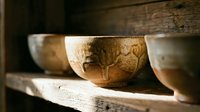 Handcrafted wooden bowls with natural grain patterns displayed on rustic shelf, showcasing traditional woodworking artistry and organic kitchen decor elements.