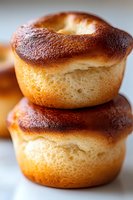 Fresh baked Yorkshire puddings stacked with golden brown crispy tops and soft fluffy centers, macro food photography showing texture and rise detail.