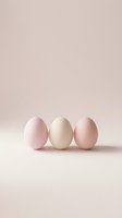 Three pastel colored eggs in soft pink beige and cream tones arranged on neutral background for Easter spring decoration and minimalist design concepts.