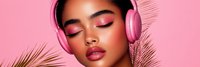 Young African American woman with pink makeup and headphones enjoying music surrounded by tropical palm leaves on vibrant pink background for lifestyle content.